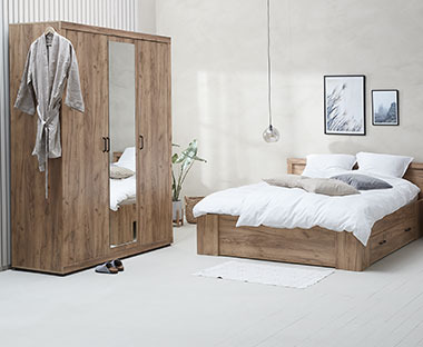 Chambre à coucher composée d'une grande armoire en bois avec un miroir, ainsi qu'un lit double en bois