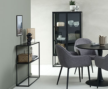 Ensemble de meubles aux couleurs sombres composé d'une table ronde, de chaises, d'une vitrine et d'une console noires