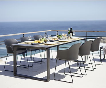 Langer Esstisch aus Kunstholz mit stylischen Stühlen auf einer Terrasse