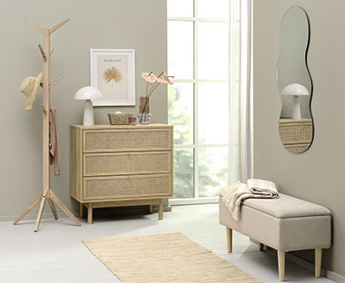 Ingresso luminoso con un tappeto, una panca in tessuto, uno specchio design, una cassettiera e un attaccapanni in legno
