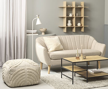 Pouf di colore naturale affianco a un divano moderno e a un tavolino di stile scandinavo