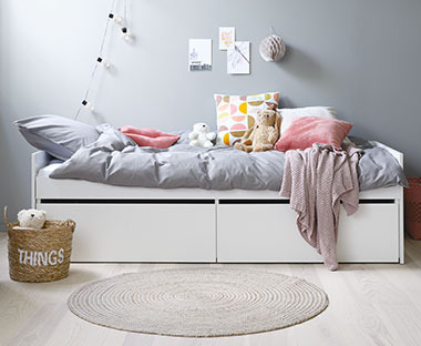 Weisses, ausziehbares Bett in einem hellen Kinderzimmer