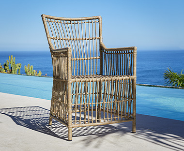 Chaise de jardin en matériau naturel sur une terrasse devant une piscine