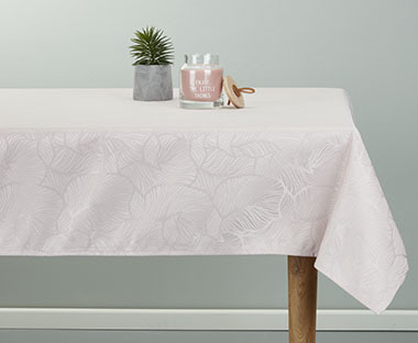 Grande table sur laquelle se trouve une jolie nappe blanche à motifs