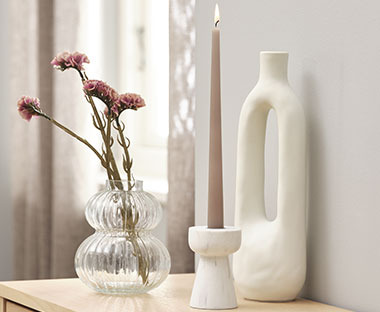 Vase tendance et chandeliers blancs, ainsi qu'une vase en verre avec des fleurs artificielles à l'intérieur
