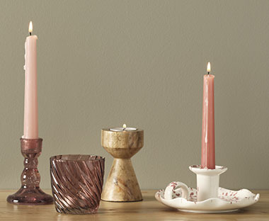 Portacandelina in vetro e tre candelieri di stile diverso con candele accesse