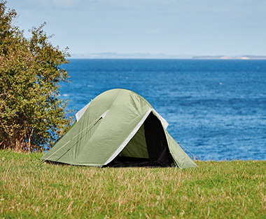 Tenda da campeggio beige e verde per 2 persone sul prato di fronte il lago