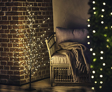 Angolo con poltrona, affiancato da alberello di Natale a rami luminosi