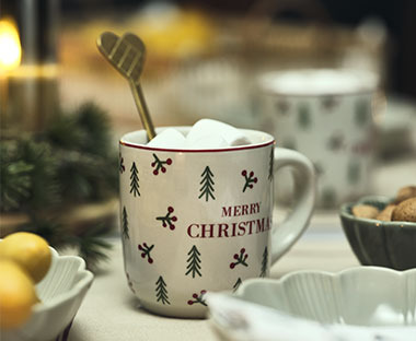 Tavola ben apparecchiata per preparativi natalizi e una bella tazza di caffé con cucchiaio dorato