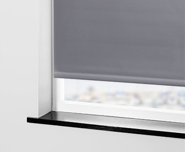 Ausschnitt eines grauen Verdunkelungsrollos an einem Fenster