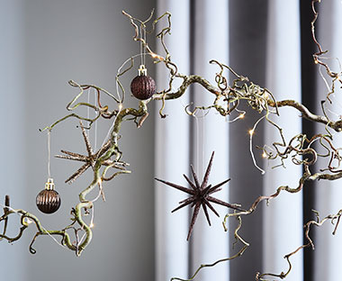 Farbige Weihnachtskugeln und Sterne hängen an einem Deko-Zweig