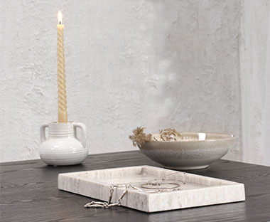 Weisser Teelichthalter mit einer Kerze darin, Dekotablett aus Marmor und eine kleine Schüssel aus Keramik
