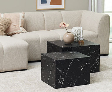 Tavolini neri effetto marmo davanti a un divano di effetto design