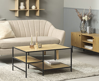 Tavolino di legno su un tappeto beige e davanti a un bel divano beige