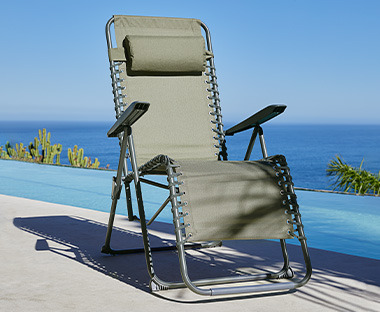 Chaise de jardin empilable en tissu beige et métal noir au bord de la mer