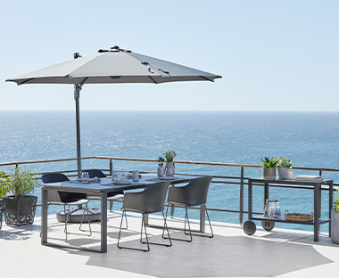 Parasol déporté sur une terrasse couvrant une table et des chaises de jardin