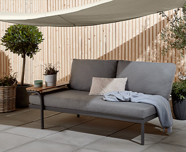 Canapé de jardin gris confortable sous un voile d'ombrage au ton clair