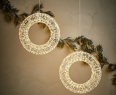 Deux couronnes de Noël à éclairage LED accrochées au mur sur une branche de pin