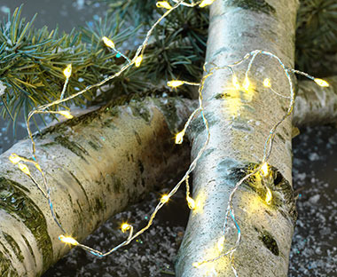 Guirlande lumineuse LED argentée accrochée à une branche de pin