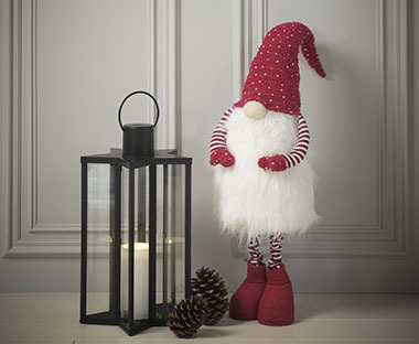 Bougie dans une lanterne, lutin de Noël rouge et pommes de pin