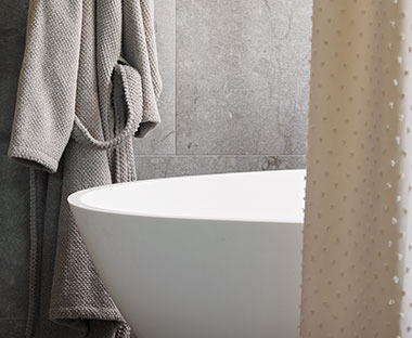 Salle de bain avec rideau de douche tendance et peignoir suspendu près de la baignoire
