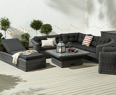 Elegante set lounge nero su terrazza soleggiata e circondata da piante
