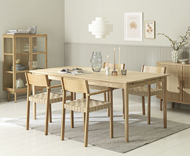 Mobili di colore chiaro comprendenti una credenza di legno, una vetrina e un tavolo circondato da quattro sedie di legnoois