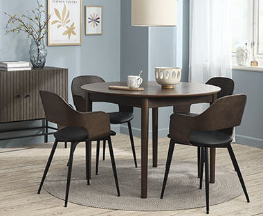Mobili di colore scuro comprendenti una credenza di legno, un tavolo rotondo di legno e quattro sedie