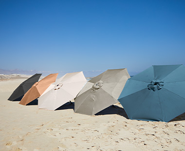 Cinque ombrelloni in cinque colori diversi in spiaggia sotto i sole 