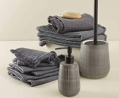 Grandes et petites serviettes en gris foncé avec distributeur de savon également en gris