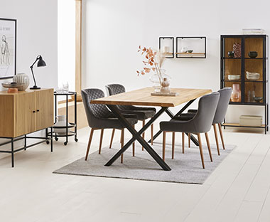 Rechteckiger Esstisch mit Holzplatte und schwarzen X-Beinen, kombiniert mit vier grauen Stühlen