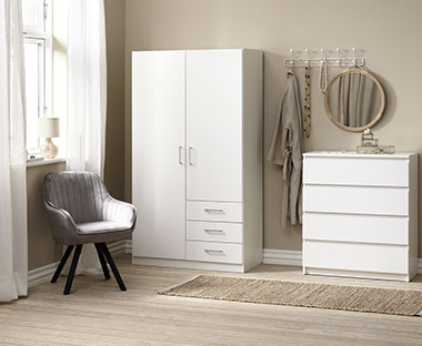 Chambre à coucher avec armoire et tiroirs blancs et chaise grise