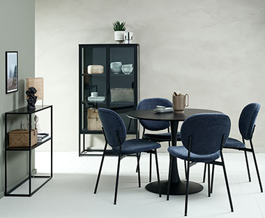 Salle à manger lumineuse avec une table noire et chaises en tissu bleu foncé