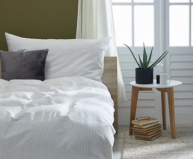 Camera da letto illuminata con letto e lenzuala bianca e tende in rosa antico 