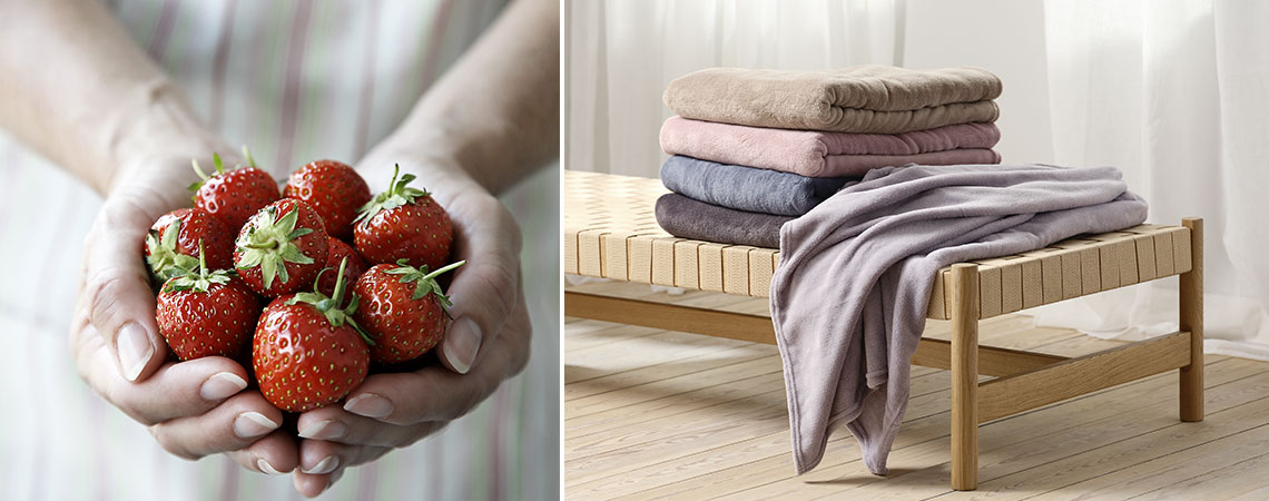 Eine Frau mit frischen Erdbeeren in der Hand und ein Tagesbett mit einem Stapel Decken in Sommerfarben 