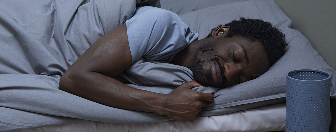 Un homme qui dort dans un lit avec un oreiller gris et une couette