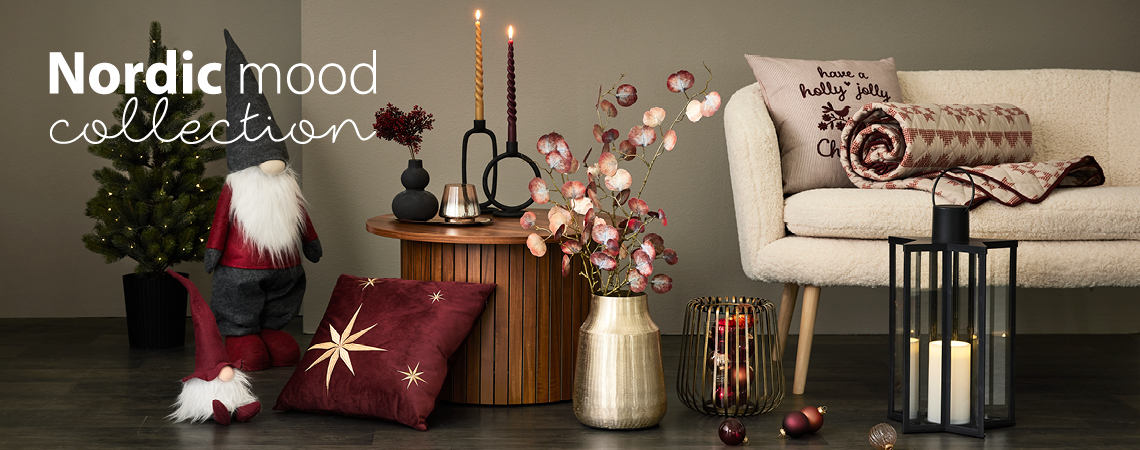 Elfi di Natale, cuscini, vaso dorato con fiori artificiali, portacandele dorato e lanterna nera davanti a un divano bianco