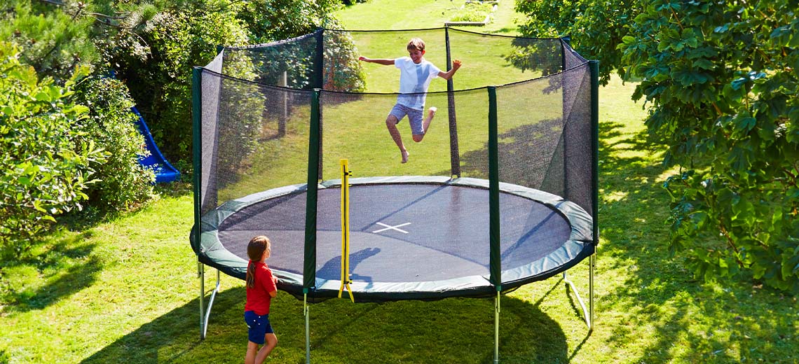 Kinder spielen auf einem grossen Trampolin im Garten 