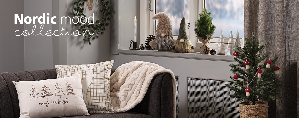 Sofa mit weihnachtlichen Zierkissen und Kuscheldecke, Fensterbank mit Weihnachtswichteln und Weihnachtsdekoration