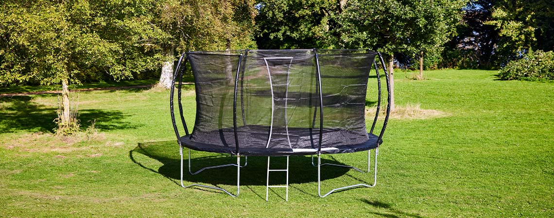 Grand trampoline sur une pelouse verte dans un jardin