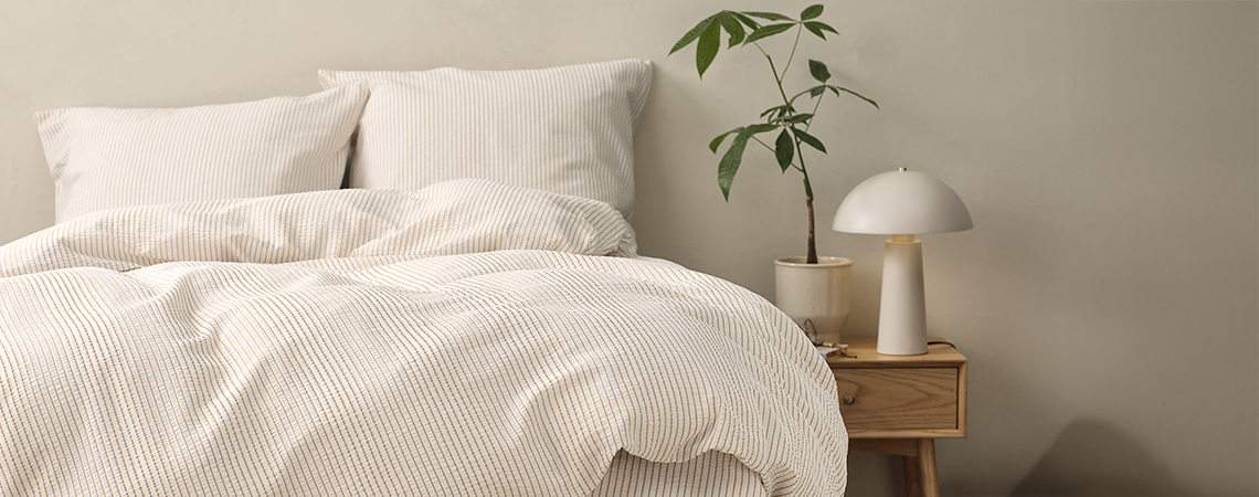 Lit avec parure de lit à rayures dans une chambre avec une table de nuit et une lampe de chevet