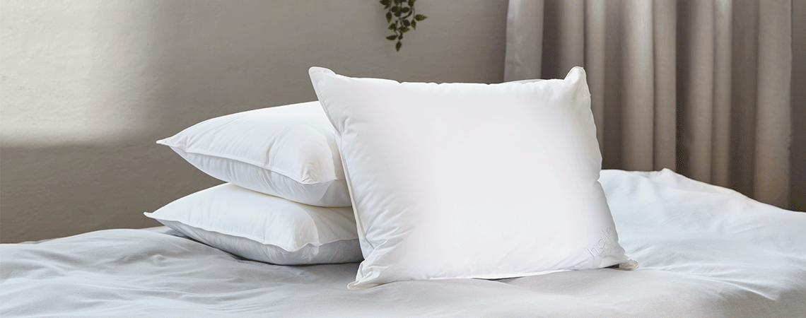 Pile de trois oreillers sans taies sur un lit