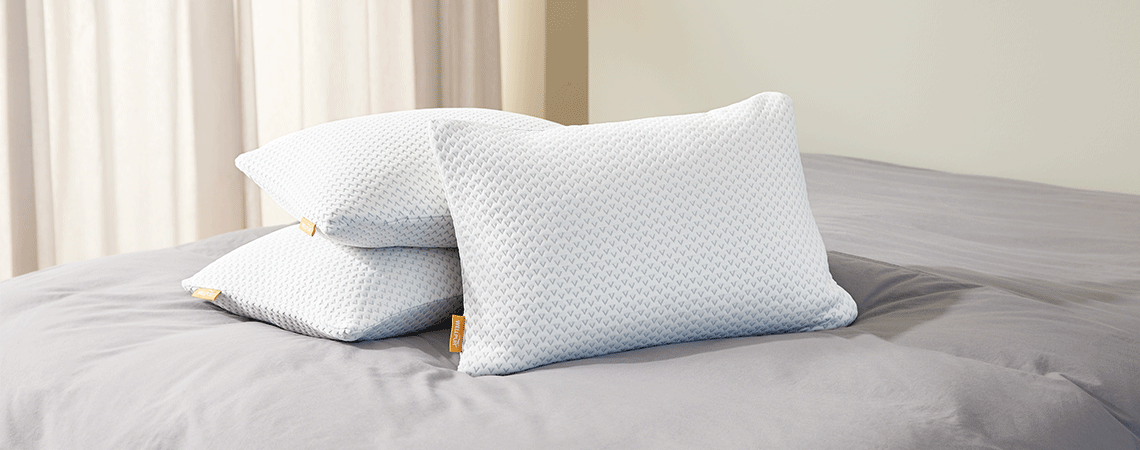 Tre guanciali diversi sulla biancheria da letto grigia