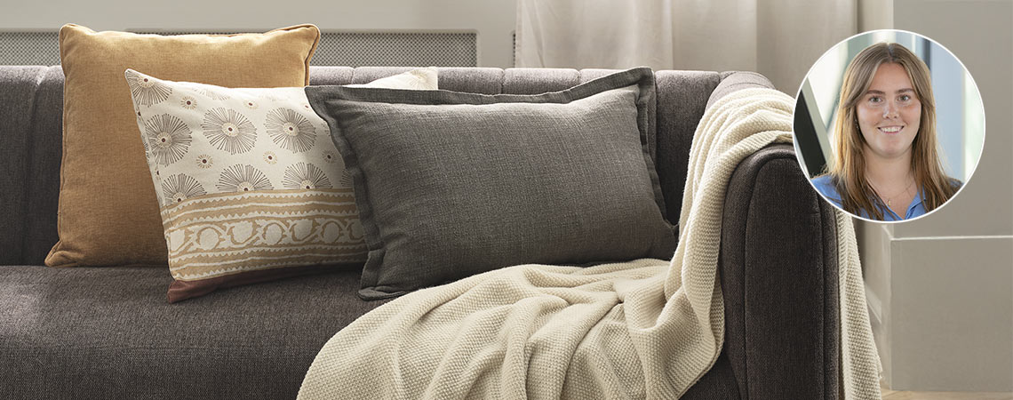 Sofa mit drei Kissen und einer Decke, gestaltet von Josefine Riis Kjeldsen. 
