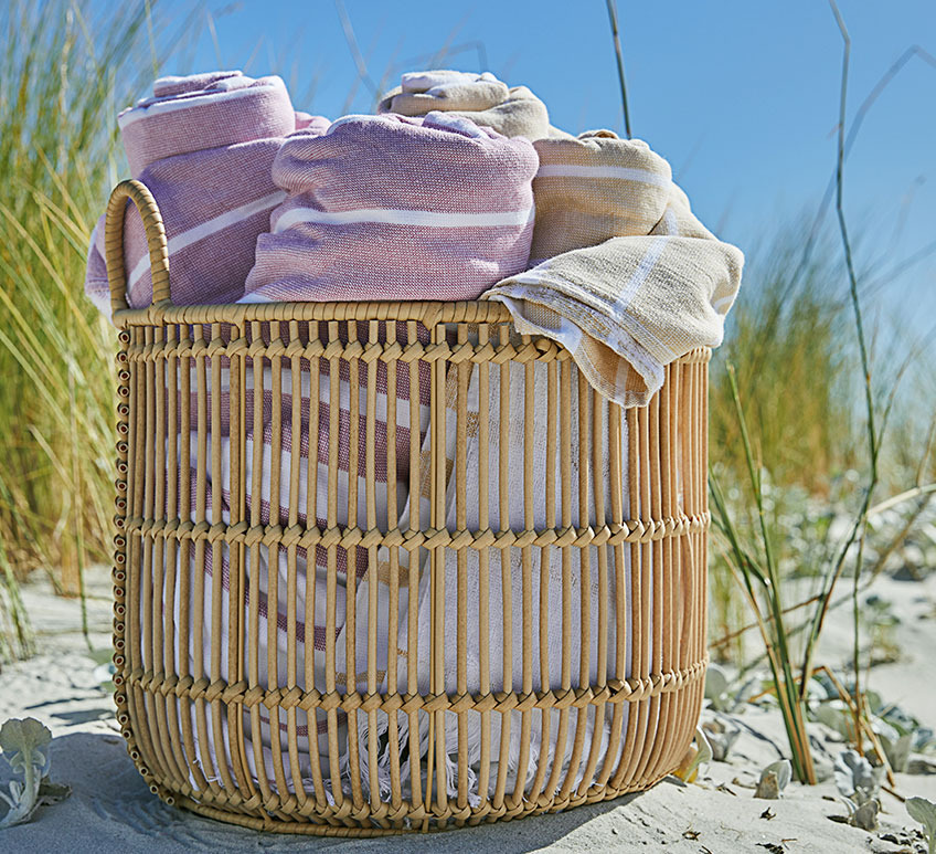 Grosser Aufbewahrungskorb mit Strandtüchern darin an einem Strand