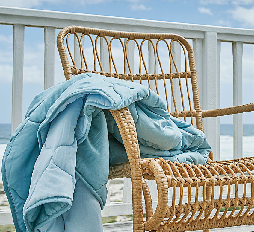 Sessel aus Rattan und ein blaues Duvet auf einer Terrasse