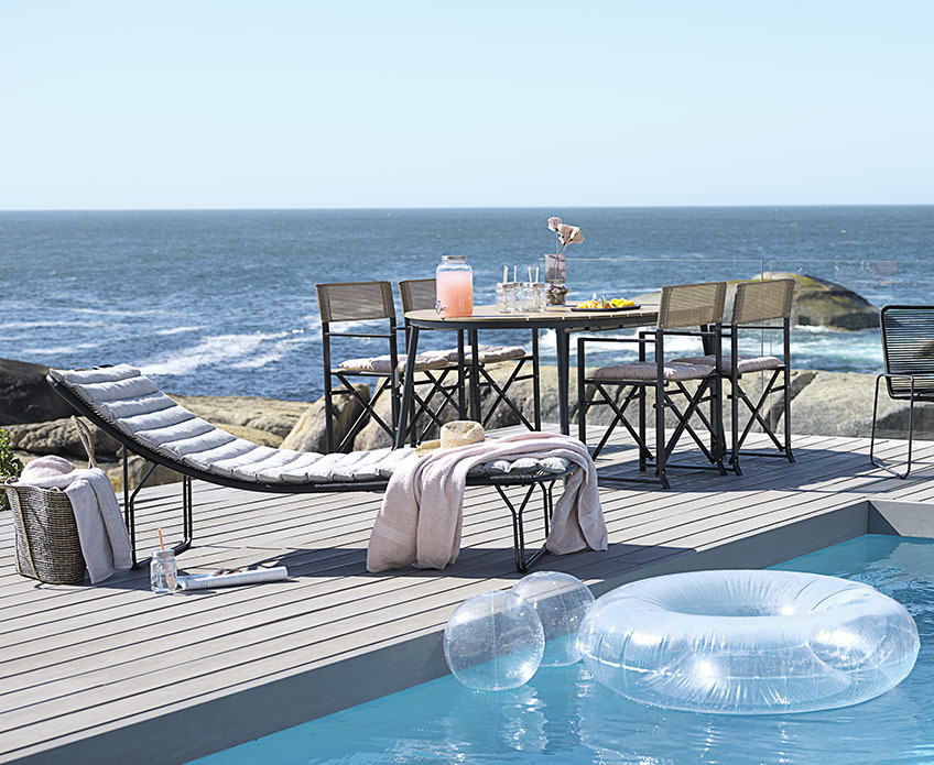 Gartenmöbel auf einer Terrasse mit Pool in der Nähe des Meeres