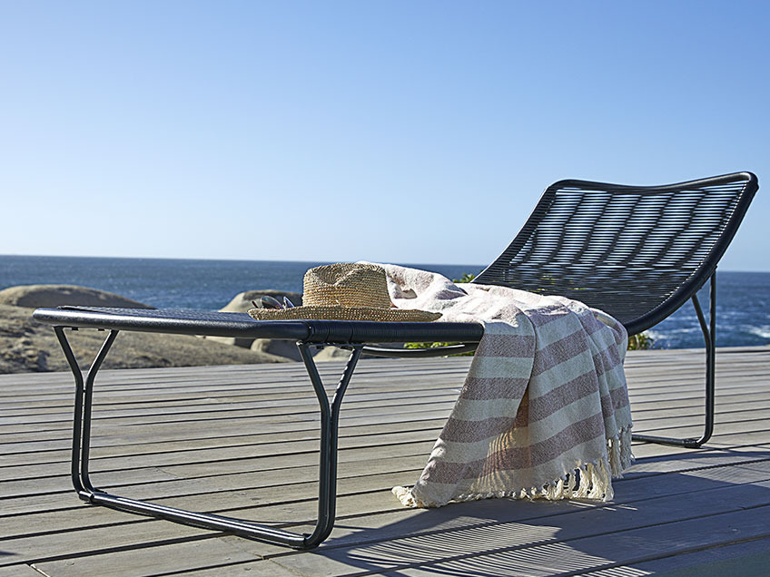 Chaise longue sur un patio en bois près de l’océan