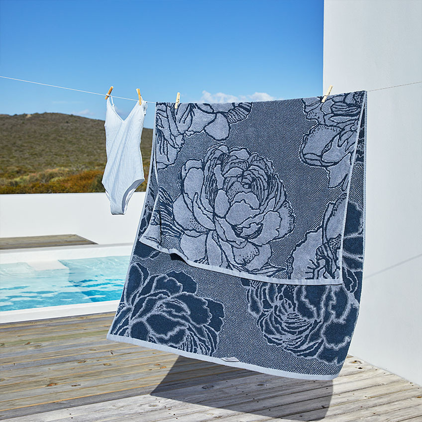 Large blue beach towel with flower pattern on laundry line