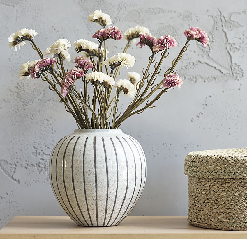 Weisse und rosafarbene Kunstblumen in einer grossen Vase mit grauen Streifen